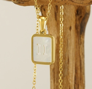 Detail der 18K vergoldeten Edelstahlkette mit Zwillinge-Muschel-Anhänger auf Holz