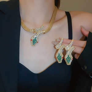 Close-up of gold snake jewelry set with green crystals and red stones on model