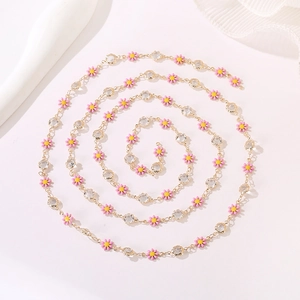 Close-up of pink daisy charm necklace with gold chain and sparkling rhinestones