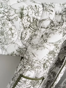 Gros plan de la veste matelassée blanche avec motifs noirs et détails de liserés verts