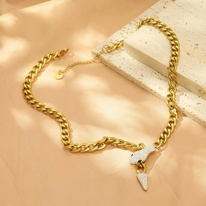 Detail of 18K gold plated Cuban chain necklace with iced-out snake pendant on stone