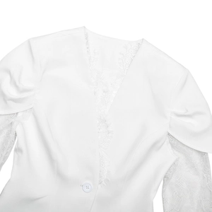 Close-up of elegant white blazer featuring lace patchwork on the collar and sheer lace sleeves