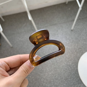 Detailed view of an amber resin hair claw clip with a glossy translucent brown finish