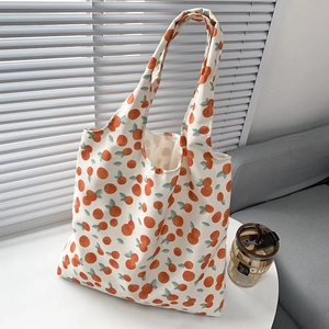 Close-up of canvas tote bag with orange fruit print on a white table in indoor setting