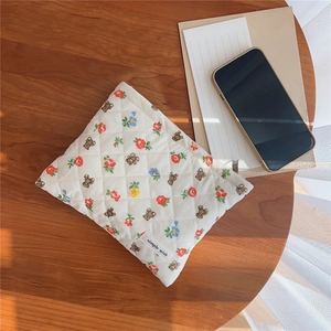 Detailed texture of quilted cotton storage bag with cute teddy bear and floral prints