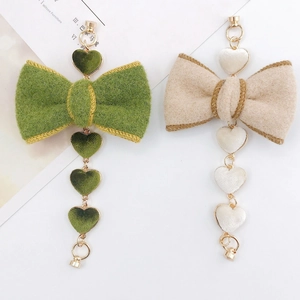 Detail of plush bow and heart pendants in sage green and cream for DIY jewelry crafts