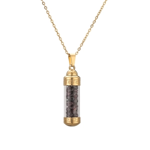 Detailed close-up of golden capsule pendant necklace with dark red stones on white background