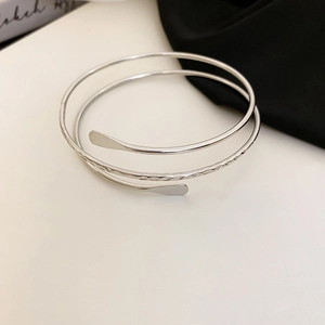 Detailed close-up of multilayer spiral silver metal bracelet with hammered texture finish