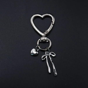 Silver metal heart keychain with bow pendant and spring clasp on black background