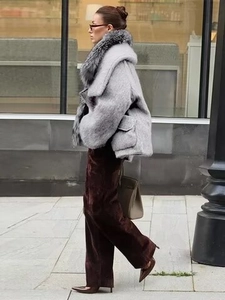 Detail of a grey jacket with a plush fur collar paired with velvet wide-leg trousers