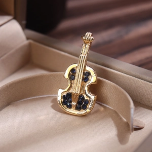 Close-up of golden violin brooch set with deep blue gemstones in a luxury gift box