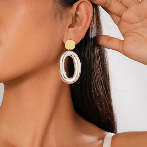 Detail view of two-tone geometric gold and silver earrings on a female model