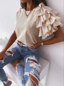 Detail of layered ruffle trim on beige short sleeve t-shirt with natural fabric drape