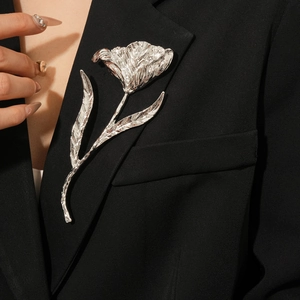 Detail of silver tulip brooch with metallic pleats on a black suit lapel