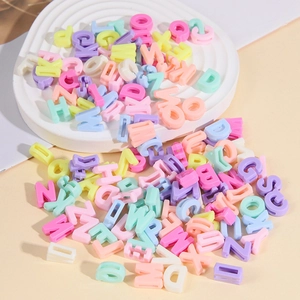 Detail of colorful acrylic alphabet beads spilling from a white tray for DIY crafts