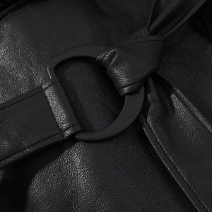 Detail shot of black leather texture and waist buckle on short shearling jacket