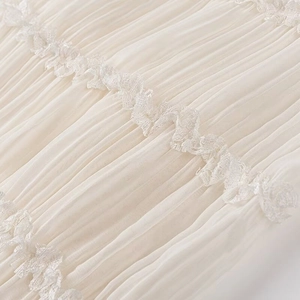 Dettaglio ravvicinato del tessuto in chiffon a pieghe crema con pizzo fine