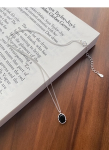 Macro detail of S925 sterling silver chain with black oval gemstone on open book page