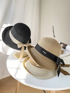 Détail de chapeaux de paille empilés en plusieurs couleurs avec grands nœuds en ruban