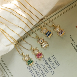 Macro view of five gold bear pendants with multicolored zircon stones on white fabric