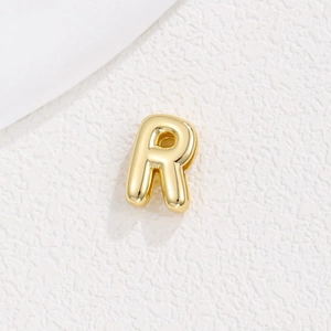 Macro shot of gold-plated 10mm metal letter R charm with a polished finish for DIY bracelets