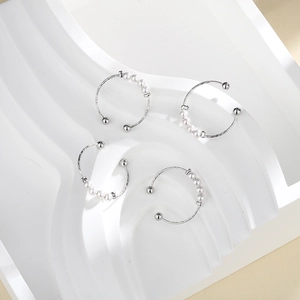 Detailed view of silver open rings featuring four white pearls on a sleek display stand