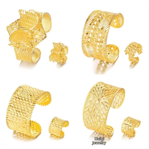 Detail of four gold hollowed-out cuff bracelet and ring sets with intricate ethnic patterns
