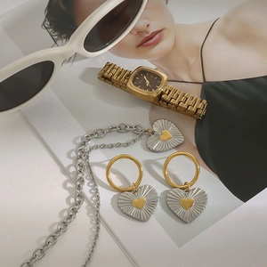 Detailed close-up of a luxury jewelry set with a gold watch and heart-shaped earrings