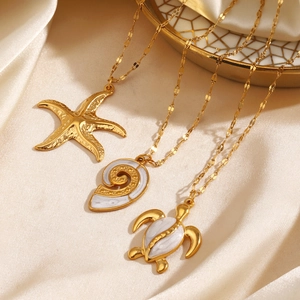 Golden ocean necklaces with starfish, conch and turtle pendants on silk background