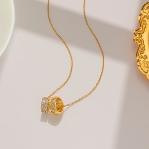 Detailed close-up of a double-ring pendant necklace in gold finish with sparkling zircons