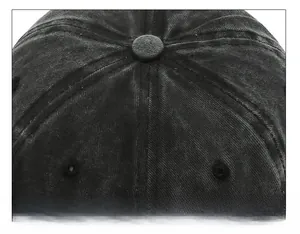 Top detail of washed black cotton baseball cap showing six-panel stitching and button