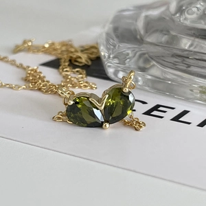Elegante goldene Halskette mit zwei herzförmigen grünen Zirkonia-Anhängern in Krappenfassung