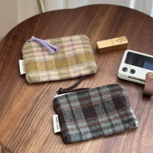 Detail of checkered fabric pouch with zipper and simple wish label on wooden table