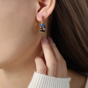 Boucles d'oreilles vintage en acier titane doré avec perles d'agate colorées portées par un modèle