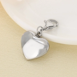 Polished heart-shaped stainless steel pendant with lobster clasp on ceramic plate