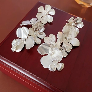 Détails de boucles d'oreilles fleurs argentées à pompons sur un coffret en bois sombre