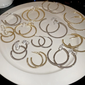 Detailed view of silver and gold C-shaped hoop earrings with pavé diamond setting on a tray