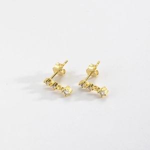 Macro shot of gold stud earrings featuring three inlaid zircon stones on white background