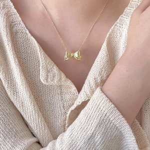 Elegant 925 sterling silver bow pendant necklace with a polished gold finish on a model