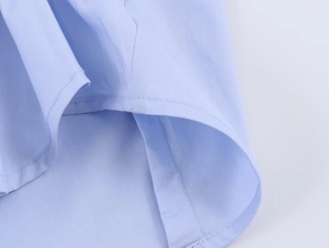 Detail view of the light blue poplin shirt featuring a curved hem and neat stitching