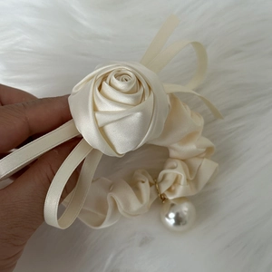Detail of cream satin scrunchie featuring a large rose flower and pearl charm pendant