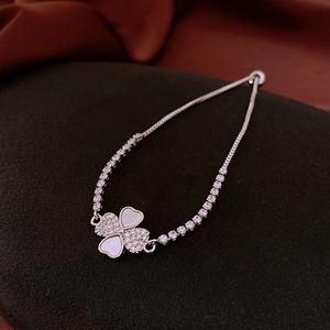 Macro detail of silver four-leaf clover bracelet with white shell inlay and crystals