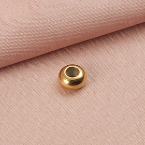 Macro view of a single gold round slider bead with smooth metallic finish for jewelry making
