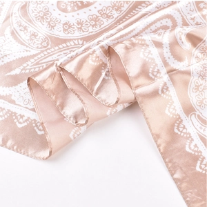 Macro shot of champagne satin scarf with intricate white paisley patterns and silk texture