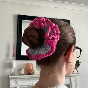 Detail of two-tone pink and grey ruffled crochet scrunchie worn on a hair bun