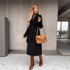 Classic black long woolen coat with V-neck lapel and tie-belt in a minimalist outdoor setting