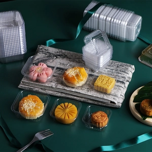 Transparent PET plastic mooncake trays for pastry packaging stacked on a green surface