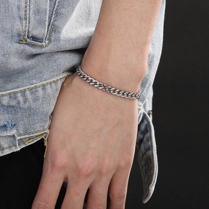 Silver Cuban chain bracelet detail on wrist styled with denim jacket for punk look