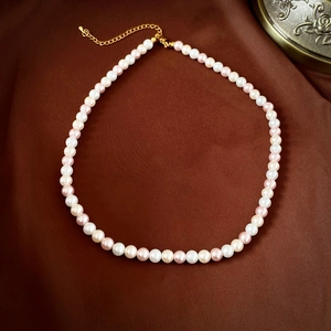 Détail du collier de perles roses et blanches avec fermoir mousqueton doré chic