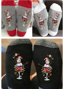 Close-up of crew socks featuring festive snowman in a wine glass with holiday lights